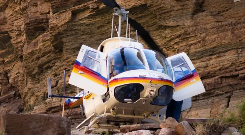 Helicopter landed on the Grand Canyon floor beside the red canyon wall